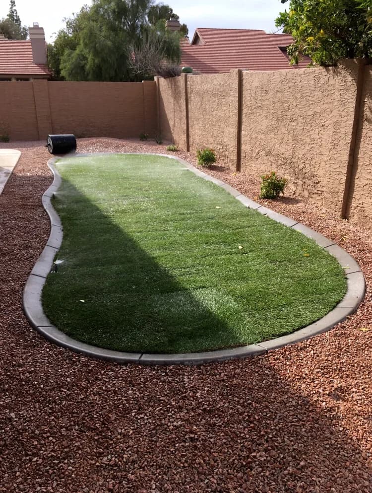 Backyard lawn with an efficient irrigation layout bordered by stone